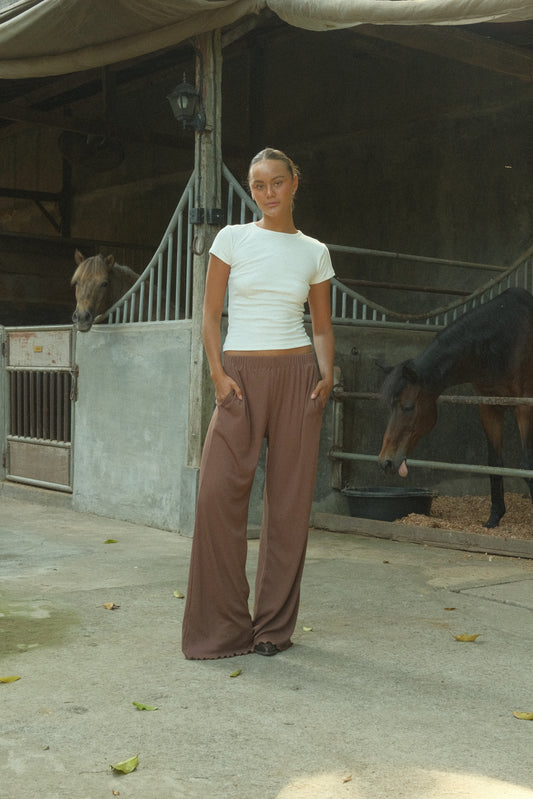 Woman wearing brown ribbed flare pants in a stable