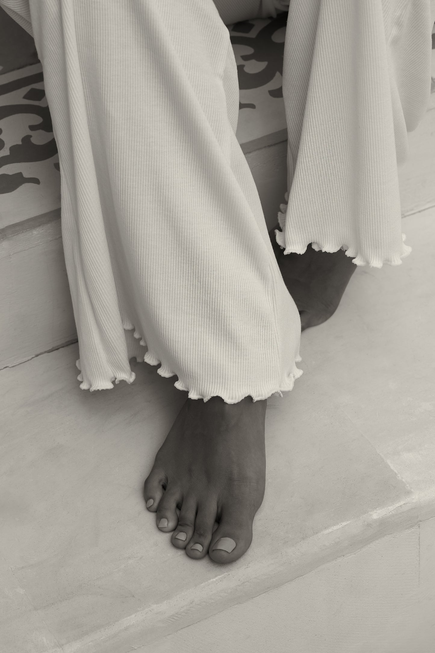 Close-up of woman's feet in white ribbed flare pants