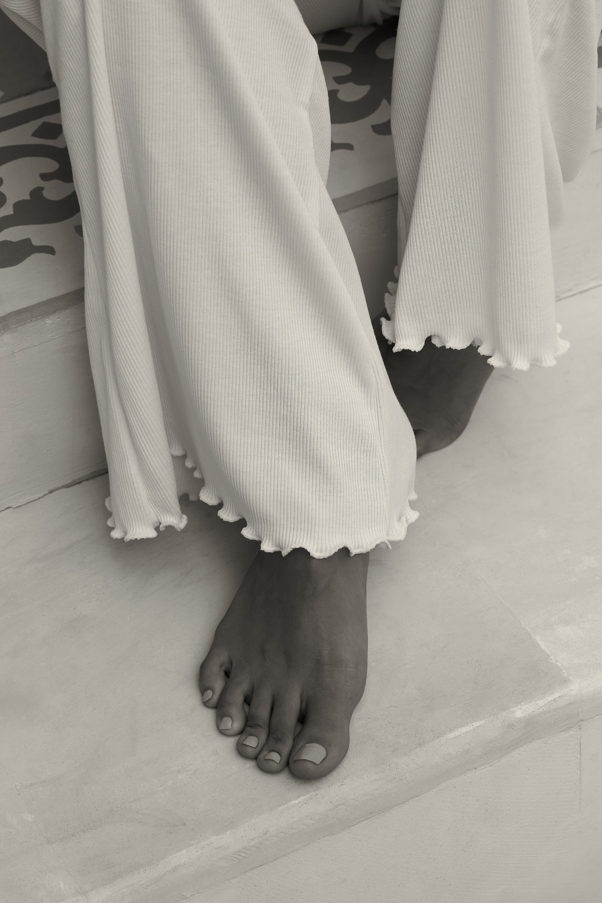 Close-up of woman's feet in white ribbed flare pants