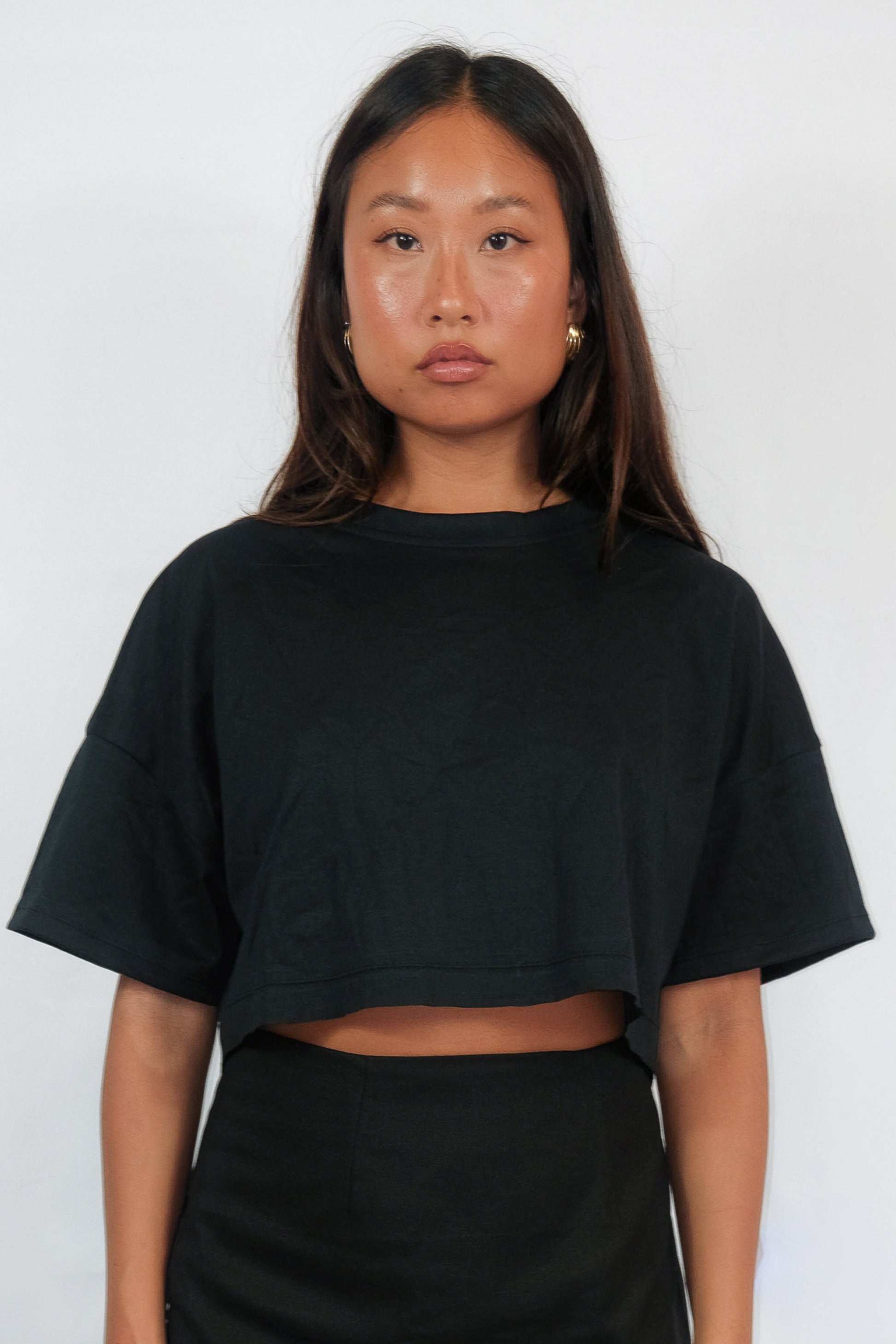 Woman in black cropped ZINA T-shirt and black skirt.