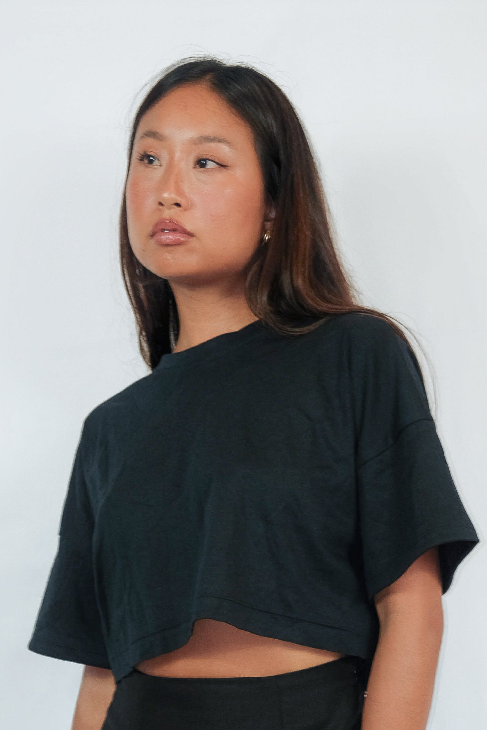 Close-up of a woman wearing a black cropped ZINA T-shirt.