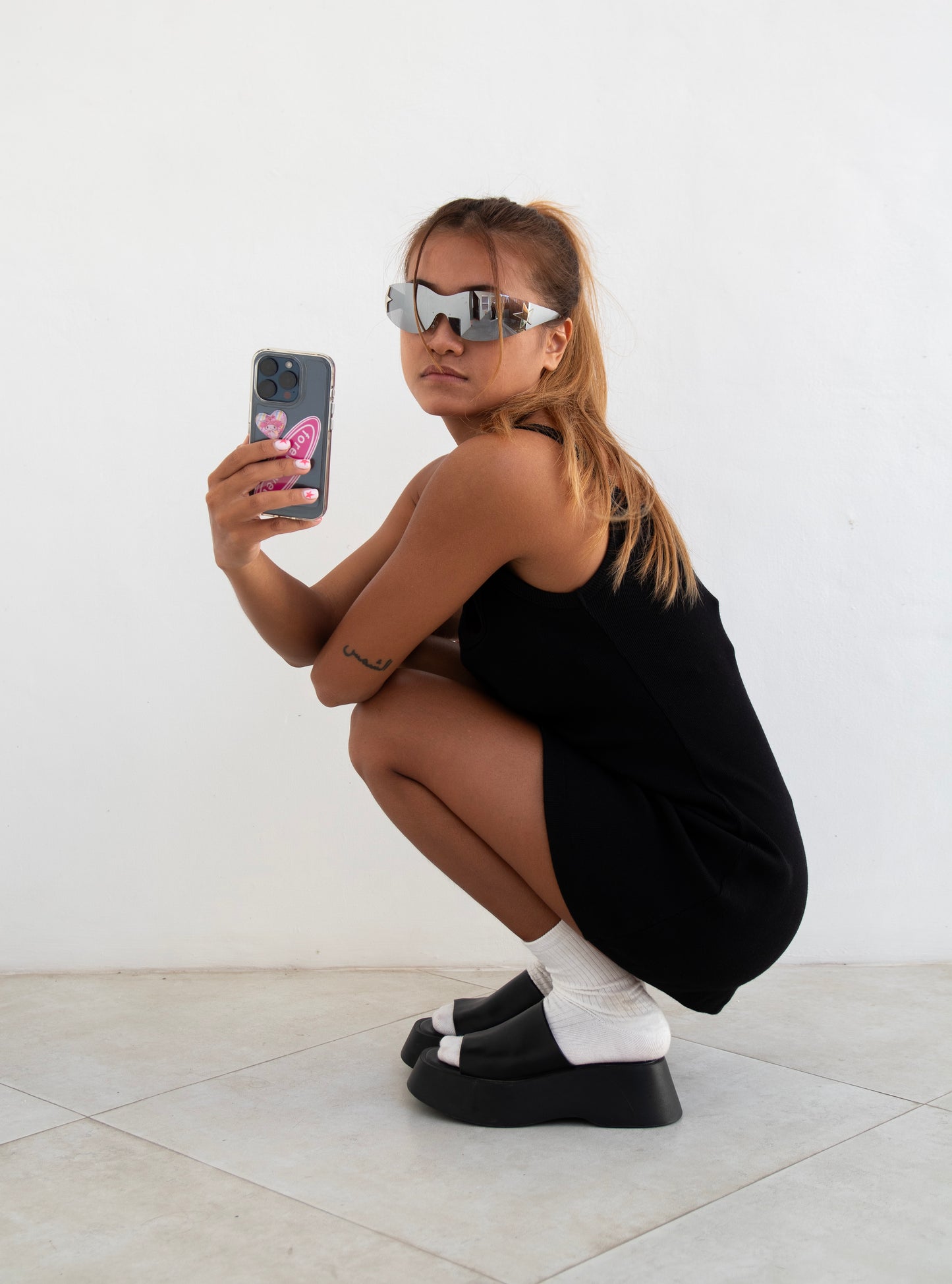 Model wearing a black SESE mini dress, holding a phone.