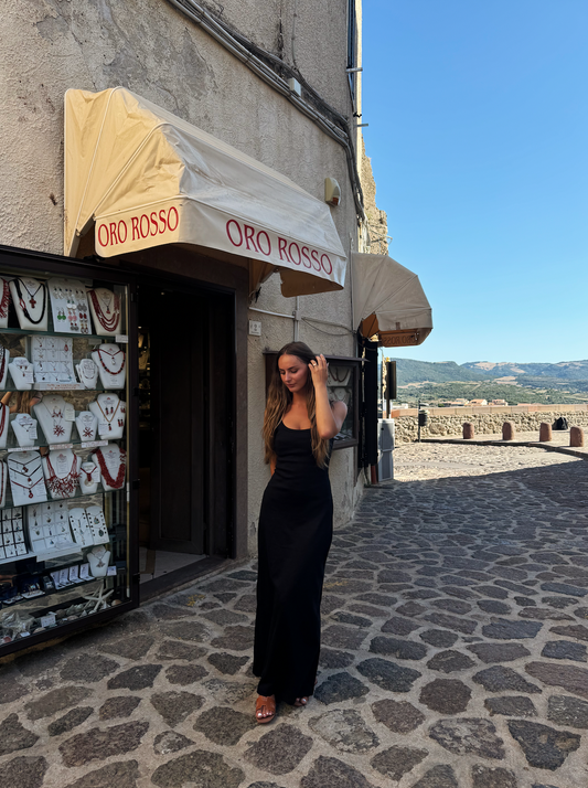 Woman in black SESE maxi dress walking down a street.